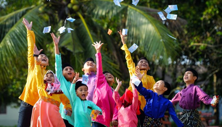 Children throw up duit raya as they celebrate Hari Raya Aidilfitri at Kg. Pengkalan Bukit in Johor. - AZHAR MAHFOF/The Star