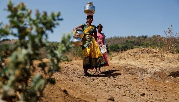 People carrying pots walk towards a well to draw water from it on a hot day in Kasara, India, May 1, 2024. REUTERS/Francis Mascarenhas