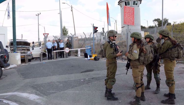 Israeli soldiers stand guard as policemen check a car damaged in a purported ramming attack at the Bell checkpoint near the illegal settlement of Beit Horon in the occupied West Bank. (File photo by AFP)