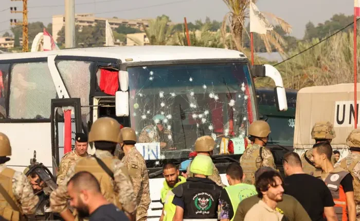 People stand next to a damaged UN bus, in the aftermath of an Israeli strike at the entrance of Sidon