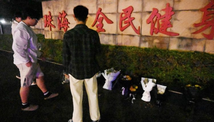 A day following the tragic destruction of the Zhuhai Sports Center by a vehicle that resulted in the deaths of numerous individuals, a group of men left flowers outside the facility.