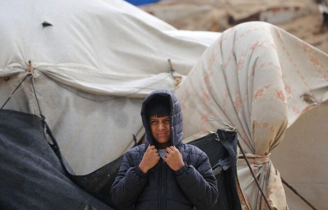 A Palestinian boy covers his head as the wind blows at a camp for the internally displaced on the beach near the Nuseirat refugee in the central Gaza Strip on December 20, 2024, amid the continuing war between Israel and Hamas. (AFP)