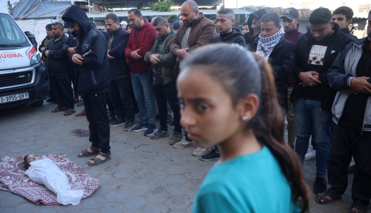 Palestinians pray over the body of a child, killed in an Israeli strike, at the Al-Aqsa Martyrs Hospital in Deir al-Balah in the central Gaza Strip
