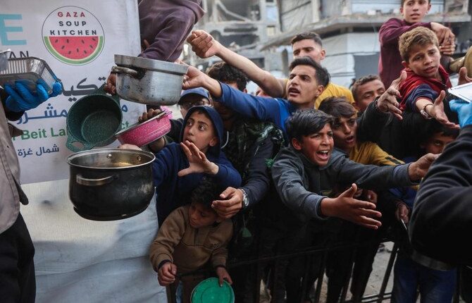 Displaced Palestinian children push into a queue to get a portion of cooked food from a charity kitchen in Beit Lahia in northern Gaza Strip, ahead of iftar during Ramadan on March 9, 2025. (AFP)