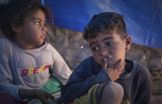 Raed Zaharna, right, and his sister Sally sit in their family tent after their mother, Ward, returned empty-handed from trying to receive donated food at a community kitchen in Khan Younis, in the southern Gaza Strip, Friday