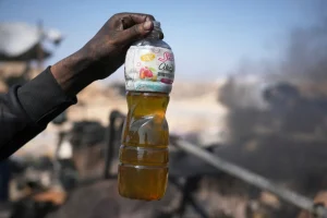 A Palestinian youth shows a bottle containing fuel made from melted plastic