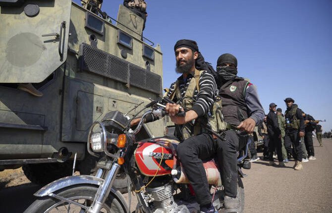 Two fighters from the Sunni Bedouin clans, ride their motorcycle as they pass by Syrian government security forces deployed on the outskirts of the Sweida province where clashes erupted between Druze militias and Sunni Bedouin clans, southern Syria, Monday, July 14, 2025. (AP)